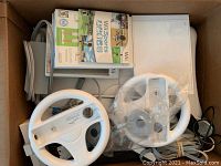 Contents of box showing console, game cases, steering wheels
