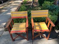 Front view of two folding directors chairs with yellow, orange, and red striped kikoy fabric seats and backs and wooden frames.