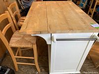 Front three-quarter view of island with butcher block top, folding leaf, and two stools