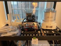 Photo showing the spiralizer with different blades, Vitamix blender base with container, and Cuisinart ice cream maker all placed on a black shelving unit.