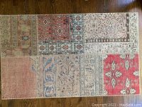 Overview of rectangular throw rug displaying its patchwork Turkish carpet remnants design in red, blue, beige, and cream colors on a wooden floor.