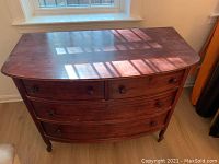 Overall view of the antique wooden dresser showing the front with four drawers and cabriole legs under natural light.