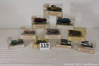 Ten antique style die cast car ornaments all in original boxes displayed in a triangular arrangement showing varying colors and models.