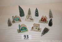 Photo shows 5 vintage cardboard Putz houses and 7 bottle brush trees arranged on a white surface with a numbered lot card.
