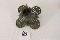 Top-down view of antique green cast iron tree stand with four circular decorative floral sections and a central cylindrical holder.