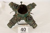 Overhead view of the entire cast iron tree stand showing four extended feet and central cylinder with screws and electrical sockets.