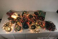 Photo of 15 strings of Christmas lights including white, multicolor, and blue bulbs, displayed tangled on a table.