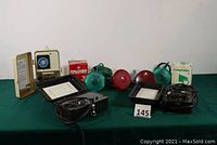 Wide shot showing both timer and control boxes along with red and green flood lights and bulb box on a green cloth-covered surface.