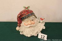Full front and slight angle view of the colorful ceramic Santa Claus cookie jar with red hat, winking face, and cardinal bird on beard detail