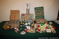 Full lot displayed on green cloth, shows multiple boxes of mercury glass ornaments, satin ornaments, and assorted decorative pieces.