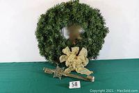 Full view of the large, lush green wreath with visible gold bow and silver snowflake door hanger placed in front.