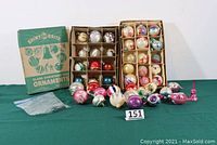 Wide shot of two open vintage Shiny Brite boxes with multiple glass Christmas ornaments, plus loose ornaments in front and original box cover.