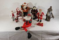 Full view of all Santa figures arranged on table showing variety in size, style, and material