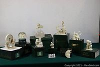 Nine Dept. 56 Snowbabies figurines displayed on green cloth, some still on original boxes including snow globe and various figurines depicting children in fuzzy winter costumes