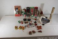 Full lot overview showing all Christmas-related vintage items, including boxed figures and various candles spread out on white background.