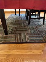 Area rug under dining table showing geometric striped square pattern in earth tones