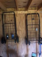 Photo of two black metal wire carts hanging against wooden wall in shed
