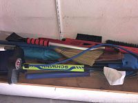 Multiple tools laid on a surface: three snow scrapers, a Schwinn bike pump, brooms, dust pans and some paperwork.