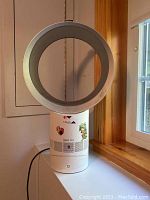 Full front view of white Dyson Cool AM06 desk fan positioned on window ledge