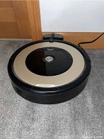 Top view of iRobot Roomba vacuum showing beige ring with black center and 'Clean' button.