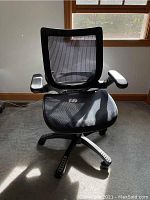 Front view of black mesh office chair showing backrest, armrests, cushioned seat, and part of the base