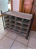 Front view showing 12 individual fabric compartments and black metal frame of shoe rack.