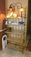 Front view of the bakers rack showing 5 wooden shelves and decorative metal frame