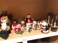 Christmas-themed figurines on shelf including multiple white cats dressed in Christmas clothes and a Santa Claus figure