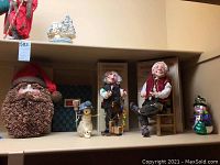 Full wide shot showing the group of nine Christmas-themed decorations placed on a beige shelf, including various Santa and snowman figurines, and other festive ornaments.