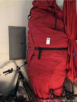 Red canvas storage bag containing the tree leaning against a garage wall next to bicycles