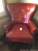 Front view of red leather tufted armchair showing button tufted back and overall condition