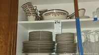 Shelved view showing stacked plates, cups, and a large serving bowl of Lenox Lace Point fine china.