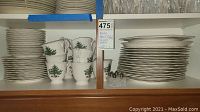 Shelves with stacked dinner plates, cups decorated with Christmas tree and holly leaf patterns.