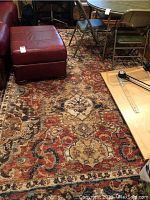 View of rug under furniture showing multi-colored floral and scroll pattern