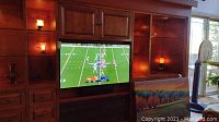 Samsung TV mounted in wooden entertainment center displaying a football game