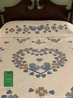 Overall view of quilt on bed showing central heart appliqué motif and scalloped edge