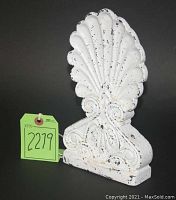 White painted antique iron door stop with shell design and scroll base, showing paint chipping and wear indicating used condition.