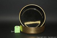 Two lacquered bowls, one resting inside the other, showing black interior and gold exterior with a glossy finish.