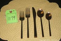 One each of salad fork, dinner fork, dinner knife, tablespoon and teaspoon arranged on a placemat