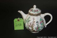 Front view of teapot with Indian Tree pattern on black backdrop alongside lot tag