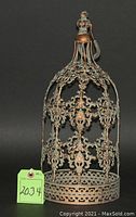 Photo of an ornate decorative bird cage with an oxidized copper finish and detailed metal filigree work with domed top and handle.