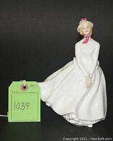 Front view of Mary figurine showing entire porcelain figure in white dress and hat with pink scarf detail.