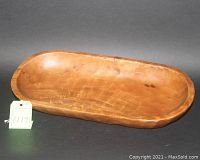 Photo shows a large elongated oval wooden serving bowl with natural wood finish on a black background with a tag marked 1117.