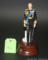 Front view of full porcelain figurine standing on wooden base with marble support