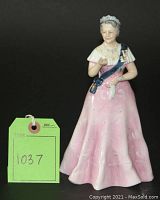 Full frontal view of Queen Elizabeth The Queen Mother figurine in pink gown on wooden base with lot tag visible