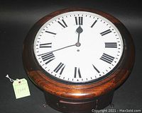 Front view of round wooden RAF wall clock showing white dial, black Roman numerals and spade hands