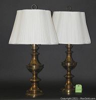 Two matching brass lamps with custom white pleated silk shades against gray background