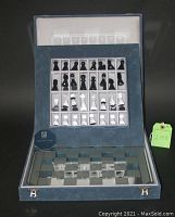 Open velvet case showing interior slots with black and clear crystal chess pieces and mirrored board beneath