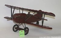 Side view of the wooden bi-plane model showcasing its detailed wings, propeller, and cockpit area.