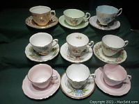 Photo showing all nine sets of cups and saucers with various floral designs and colors.